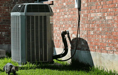 An outdoor HVAC unit stands next to a red brick house,