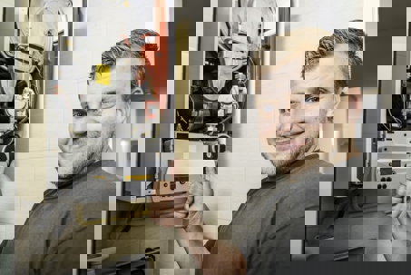 A smiling furnace technician gives a thumbs up next to an open residential furnace