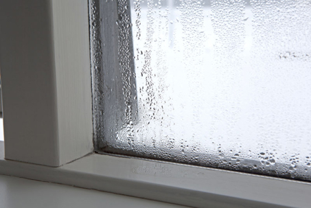 A close-up shows condensation droplets running down a window pane,