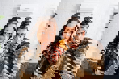 A cold couple, wrapped in blankets on a couch