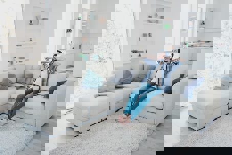 A man relaxes comfortably on a clean sectional sofa in a bright,