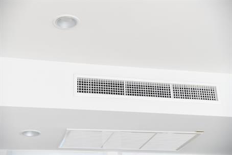 A bright white ceiling features a long rectangular air conditioning vent and recessed lighting.