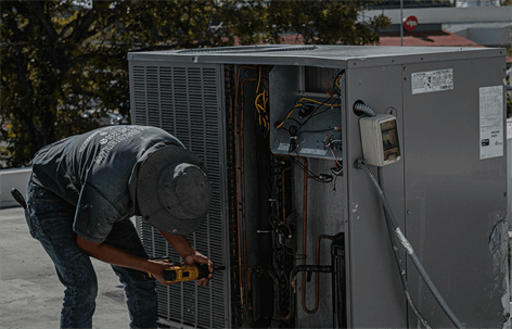 An HVAC technician repairs an outdoor air conditioning unit