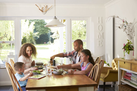 A family of four shares a meal around a bright dining table.
