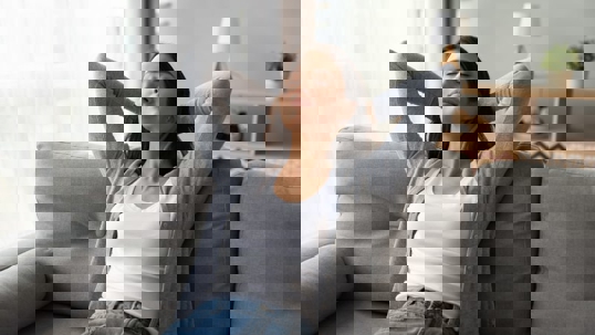 A peaceful woman reclines on a gray couch