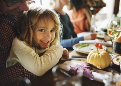 A happy child smiles at a family dinner table